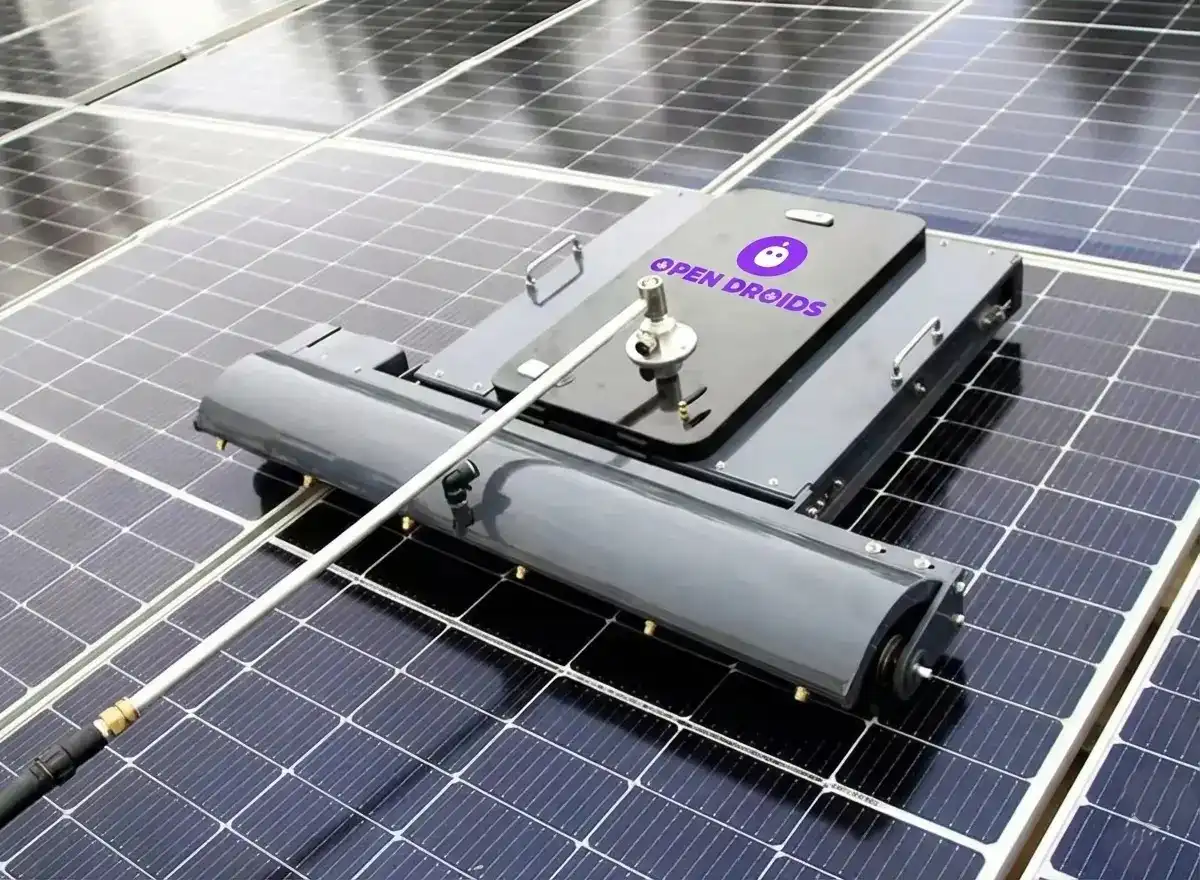 Close-up low-angle shot of solar robot moving along panel, dust flying off