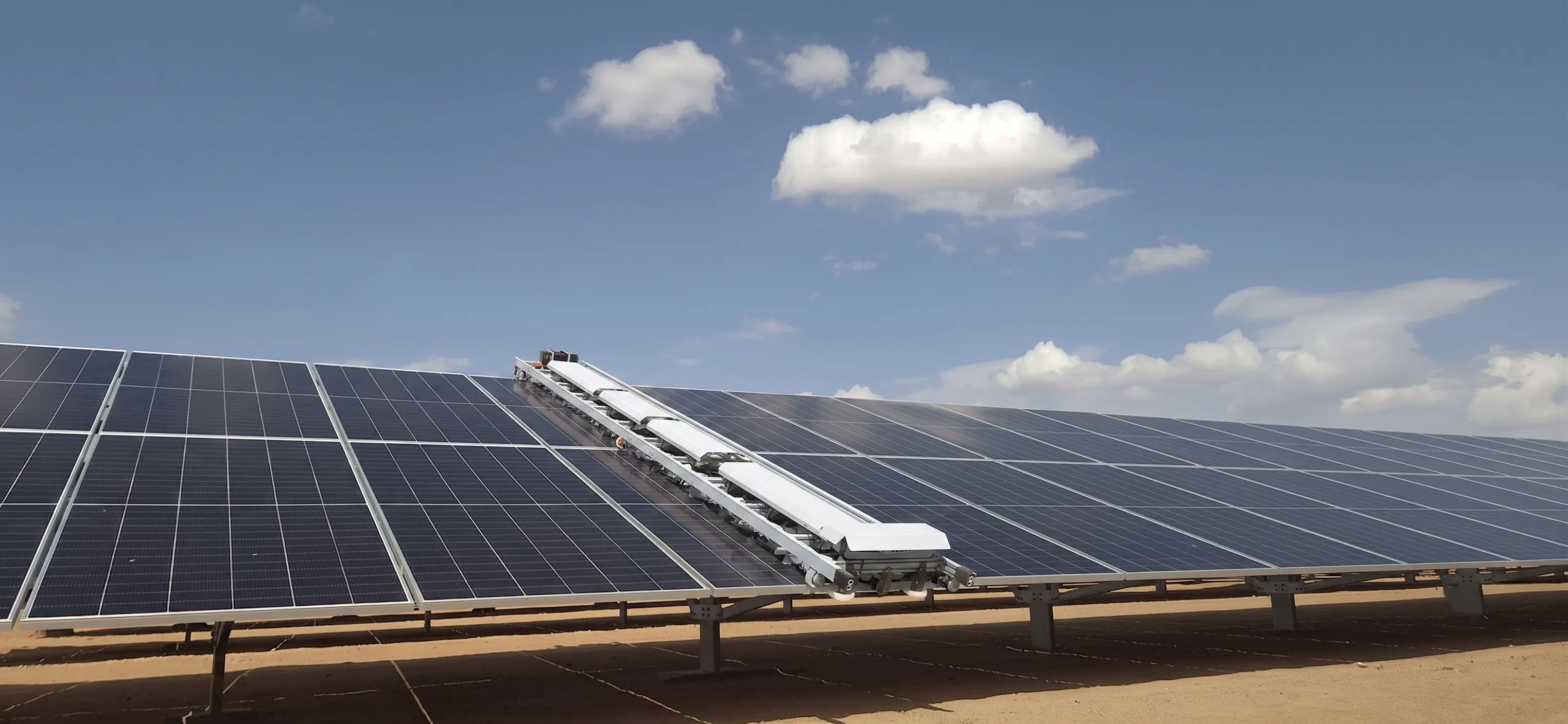 OpenDroids robot operating on a desert solar farm with visible dust terrain and panel rows in early-morning light